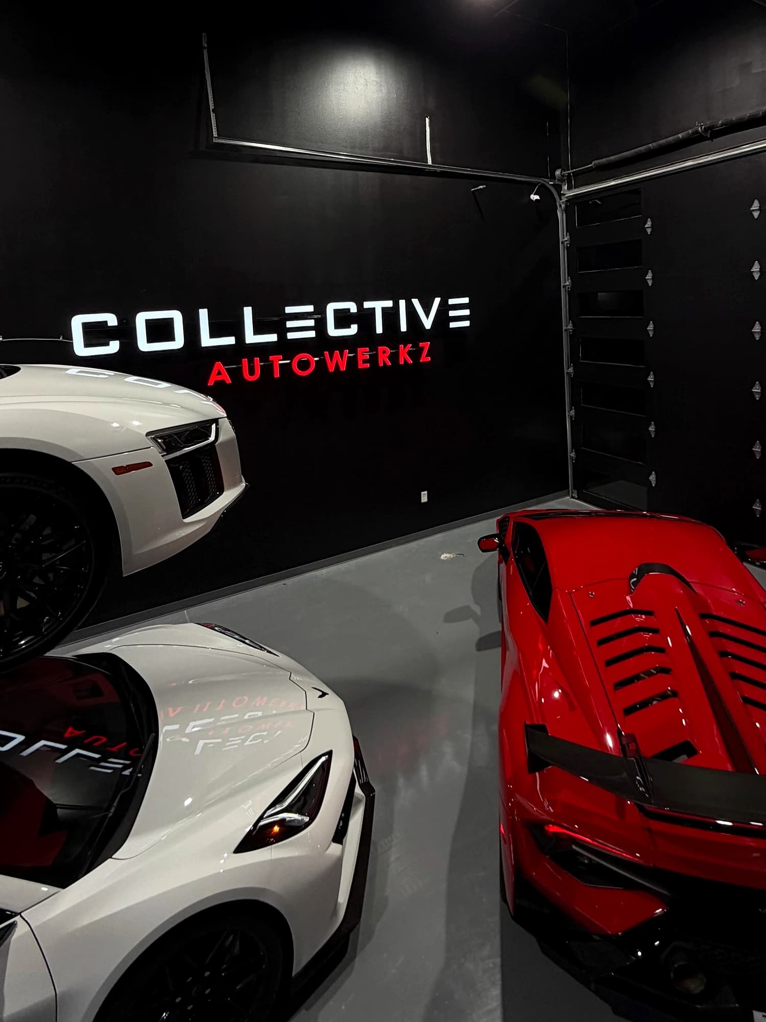 The Collective Autowerkz sign with an Audi R8, Corvette, and Huracán STO on the shop floor